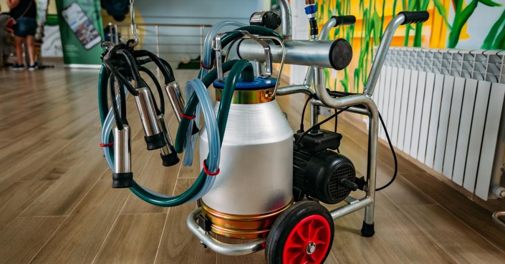 A portable milking machine has a single milking bucket. All of the parts are clean, including the transparent hoses.